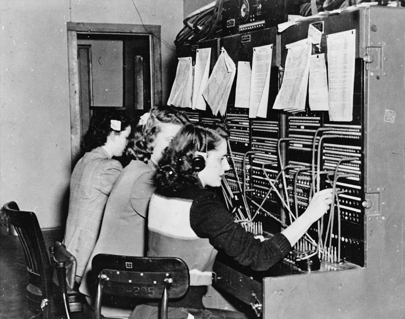 Tres telefonistas conectan llamadas con cables en una centralita en 1950.
